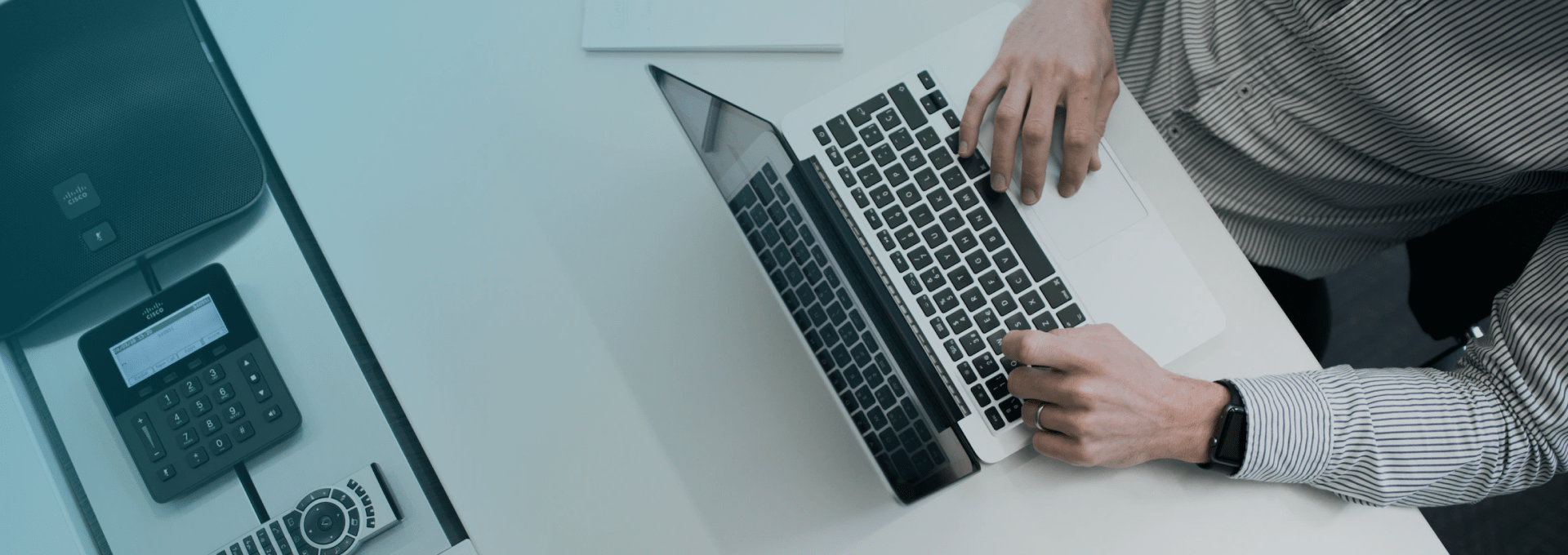 Top-down view of a laptop and conference phone on a desk